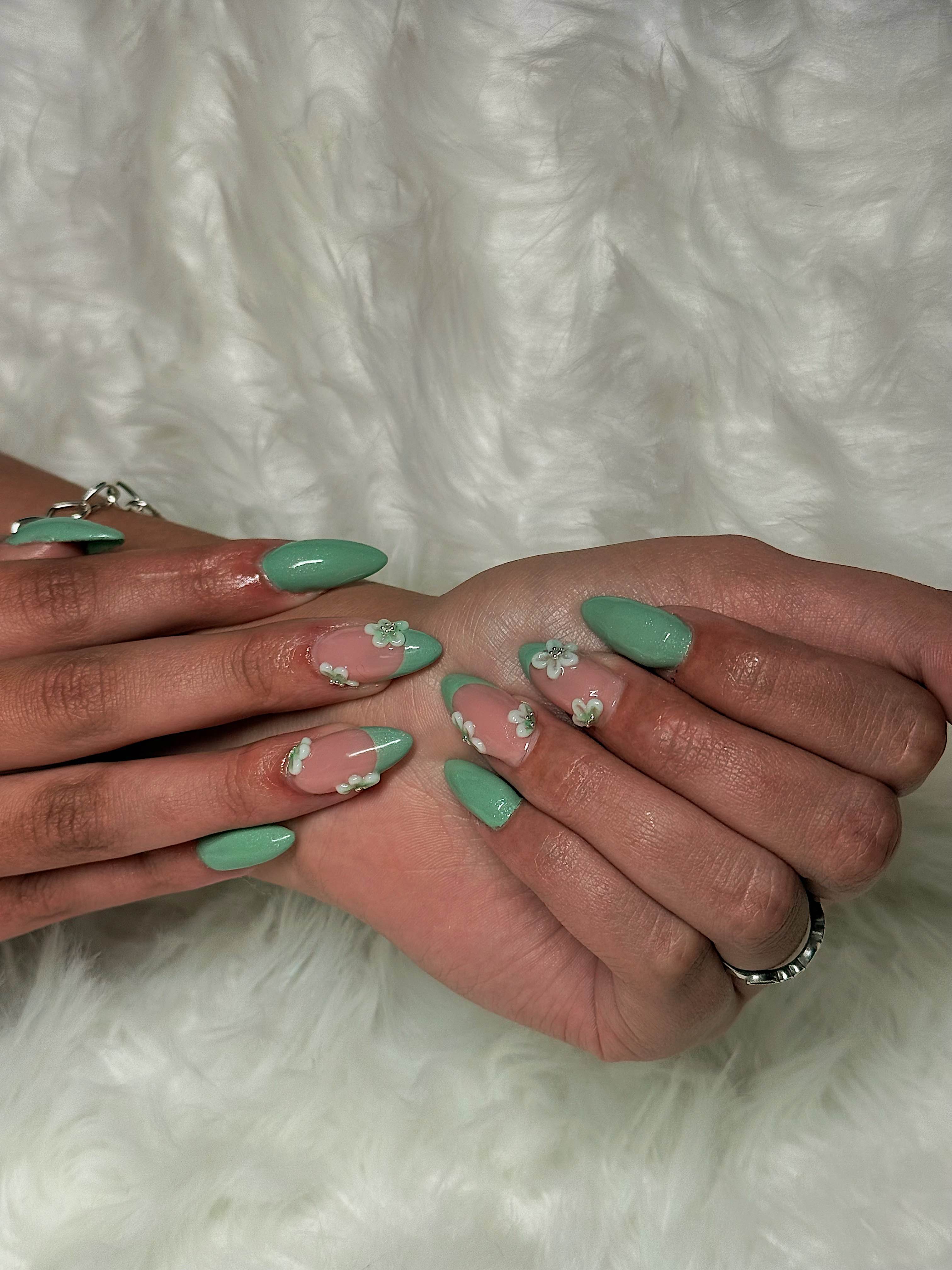 Sage green nails with 3D floral accents, silver beads, and glitter